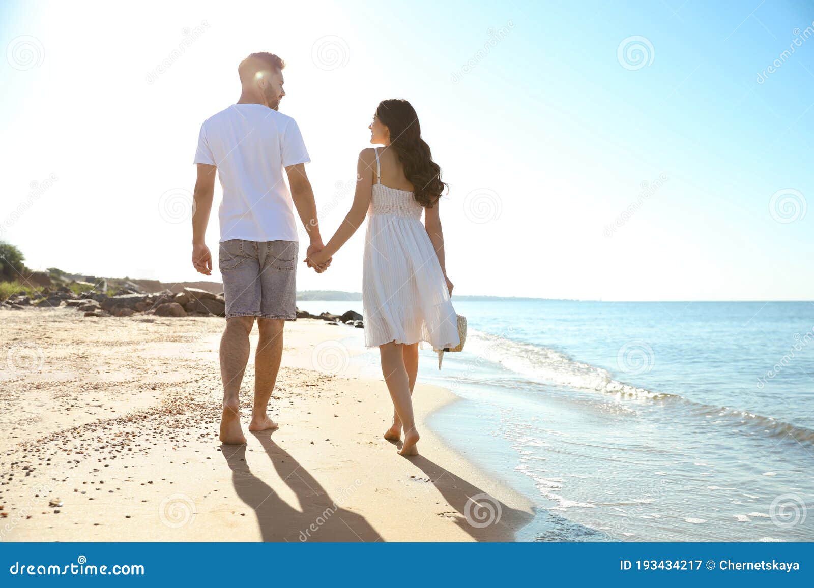 A couple enjoying a romantic walk on a beach during sunset.